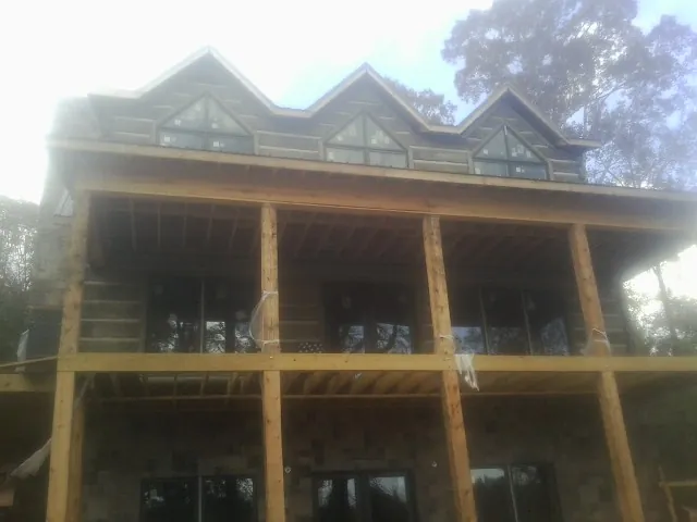 Dormers and porch framing on a large log home under construction — Roof Coating work by our crew in Glenville