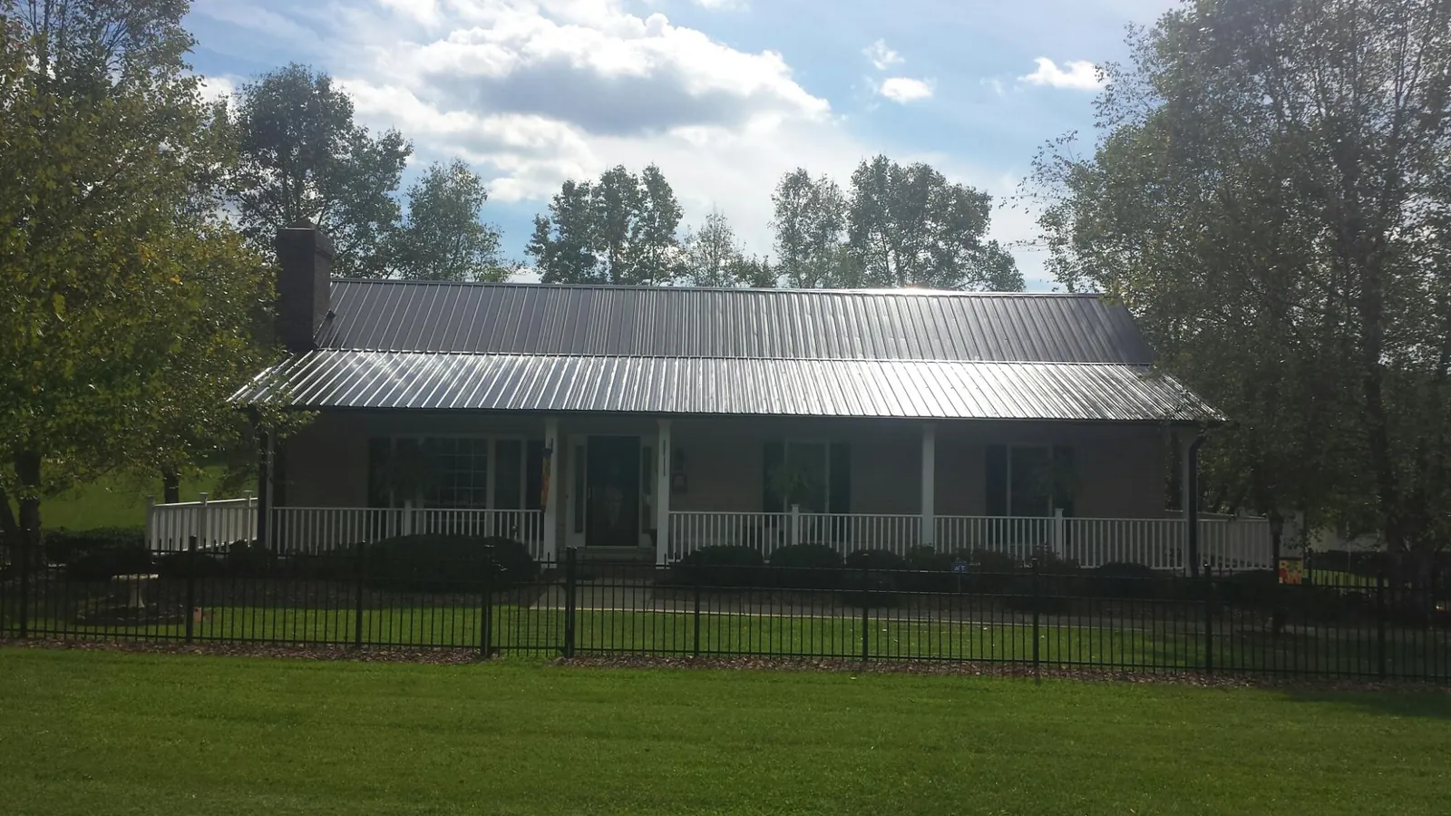 Gray metal roof on a brick ranch with a full width front porch — Gutter Guard Installation work by our crew in Glenville